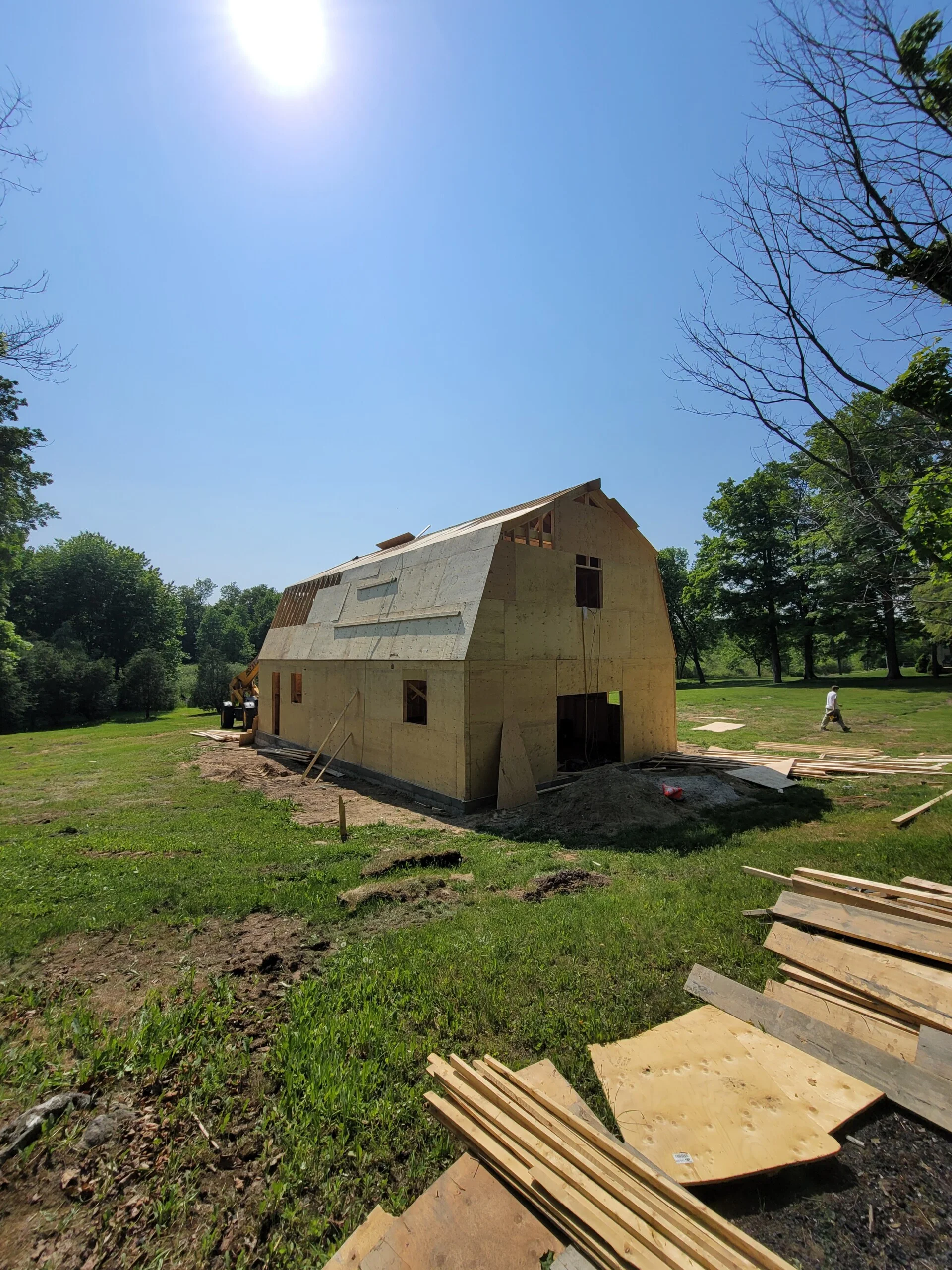 An exterior view of the framed building with plywood wall and roof sheathing in progress.
