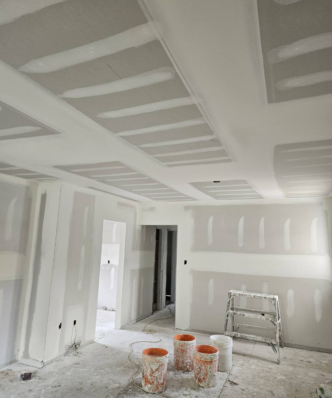 Taped drywall joints across ceiling sections, soffits, and walls, with finishing work in progress.
