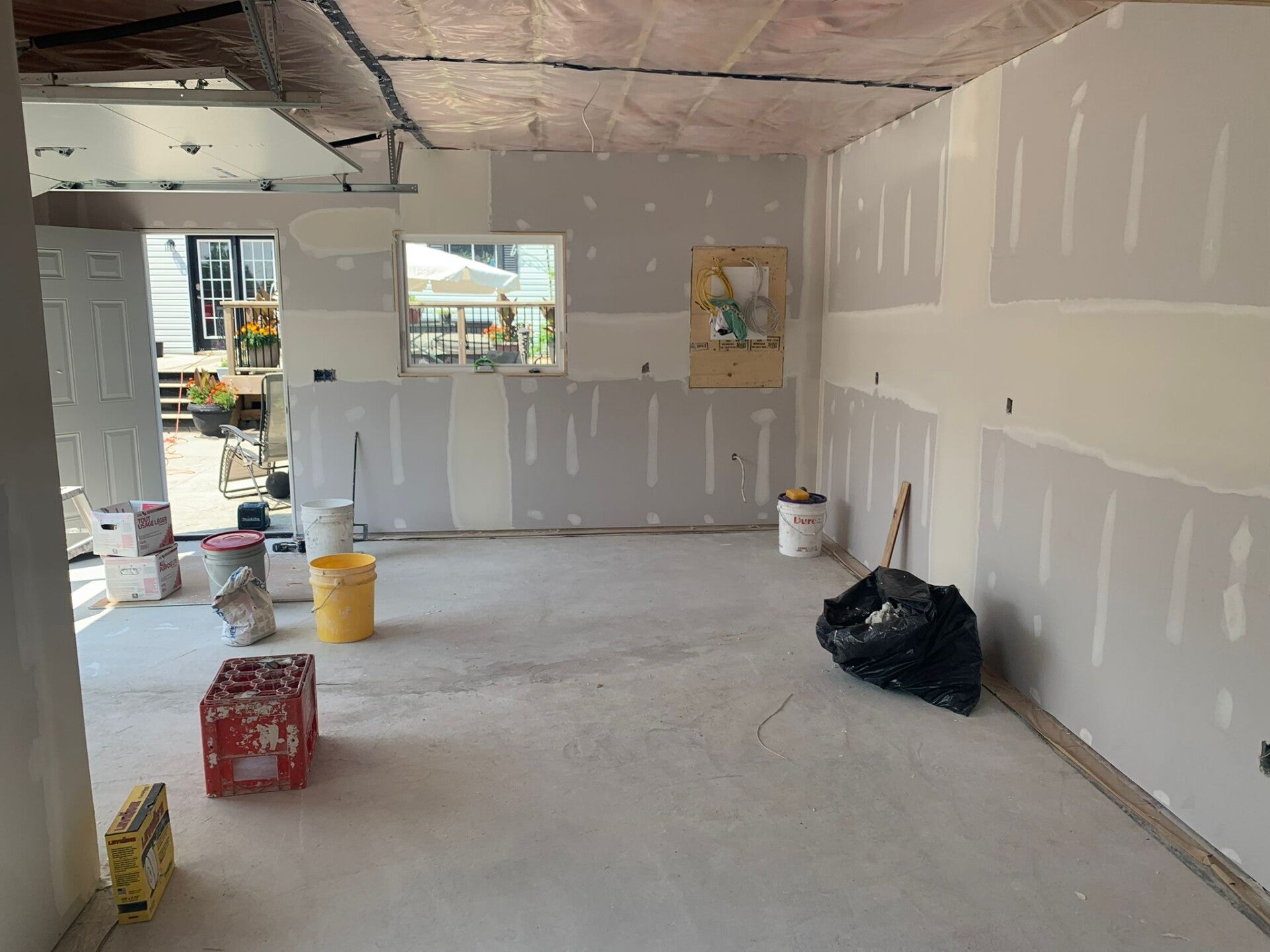 Taped drywall around a garage window and entry door, with joint compound across seams and fasteners.