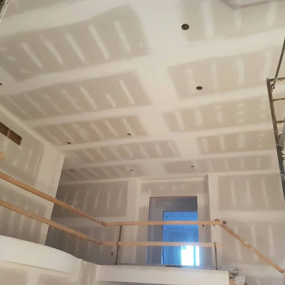 Drywall boarding and taped joints across tall walls and a high ceiling.