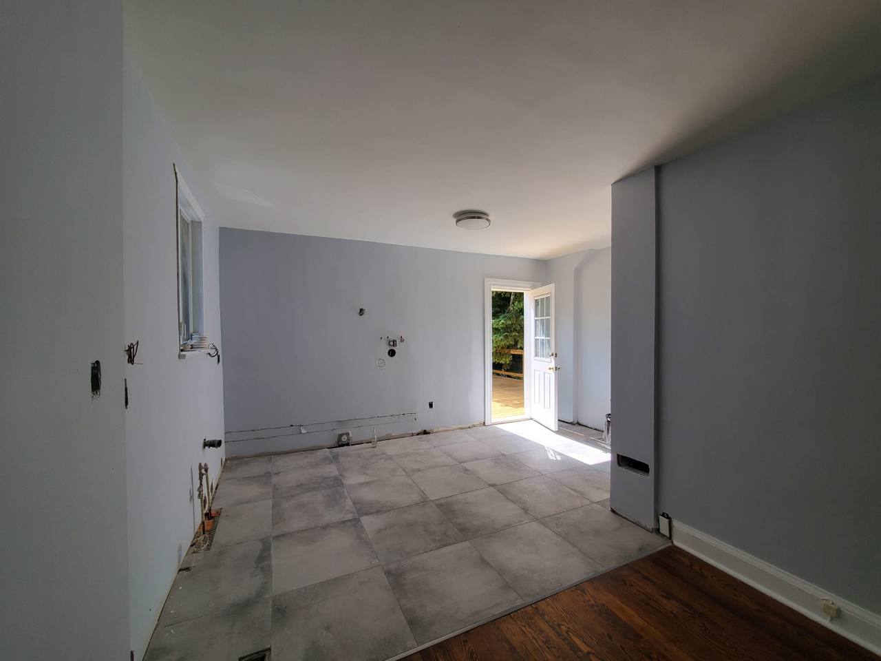 Large-format tiles across the cleared kitchen, with a straight transition to the adjoining wood floor.